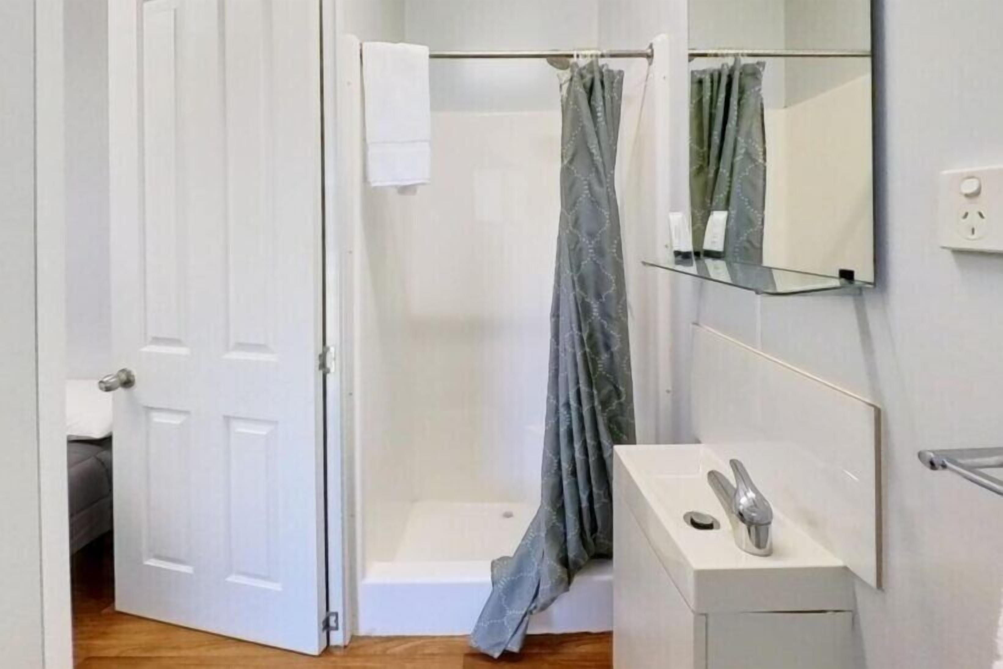 Une salle de bain avec une douche, un lavabo et un miroir.