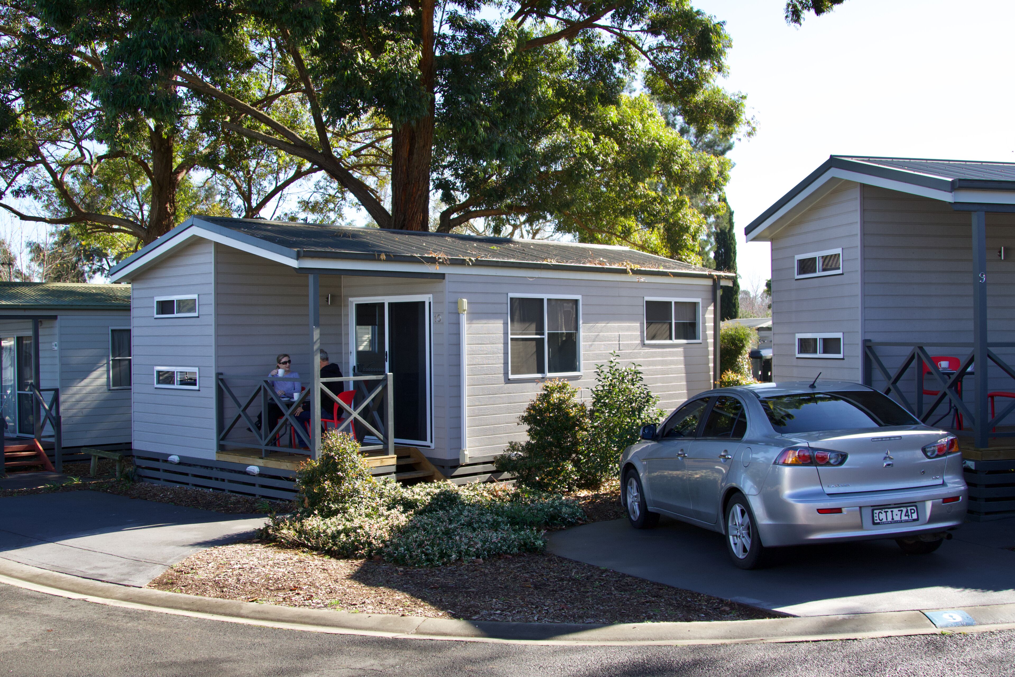A single-story mobile home with a car parked in front.