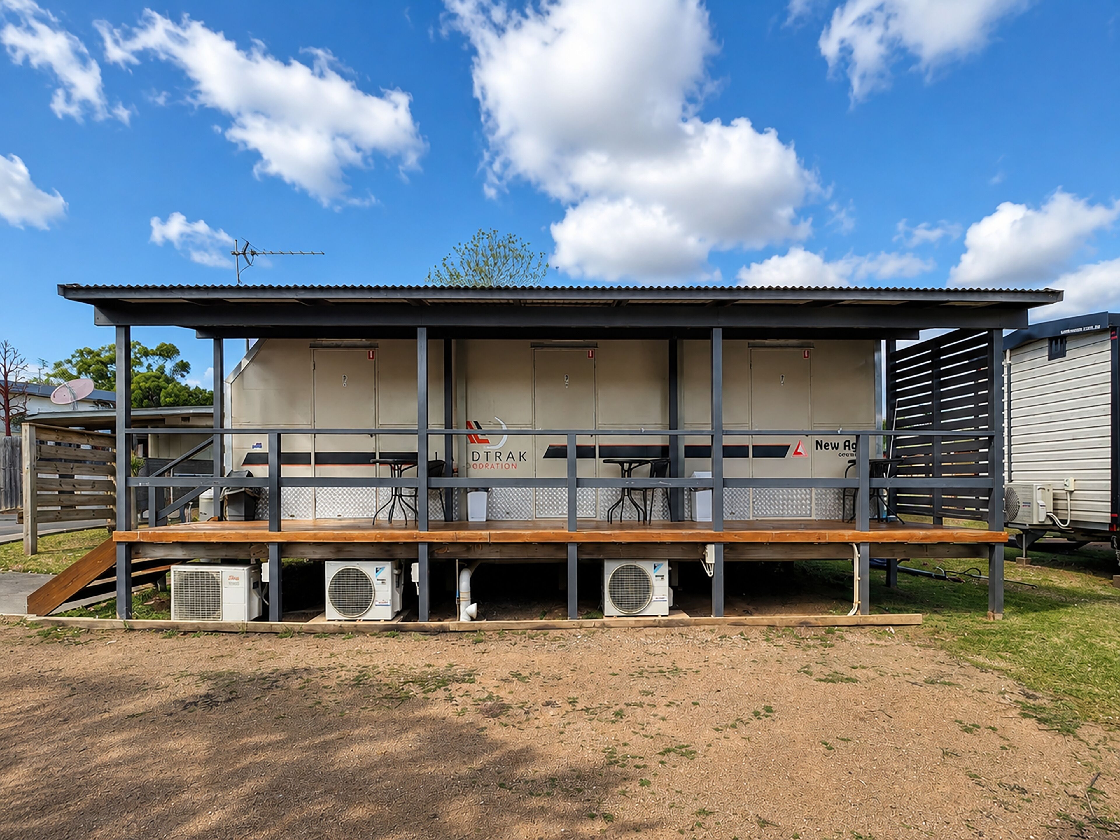 Un bâtiment doté d’un toit en métal, de plusieurs pièces et d’un espace extérieur abrité avec des tables et des chaises.
