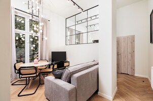 Uma sala de estar moderna com um sofá, uma mesa de jantar com cadeiras, uma televisão e um espelho grande.