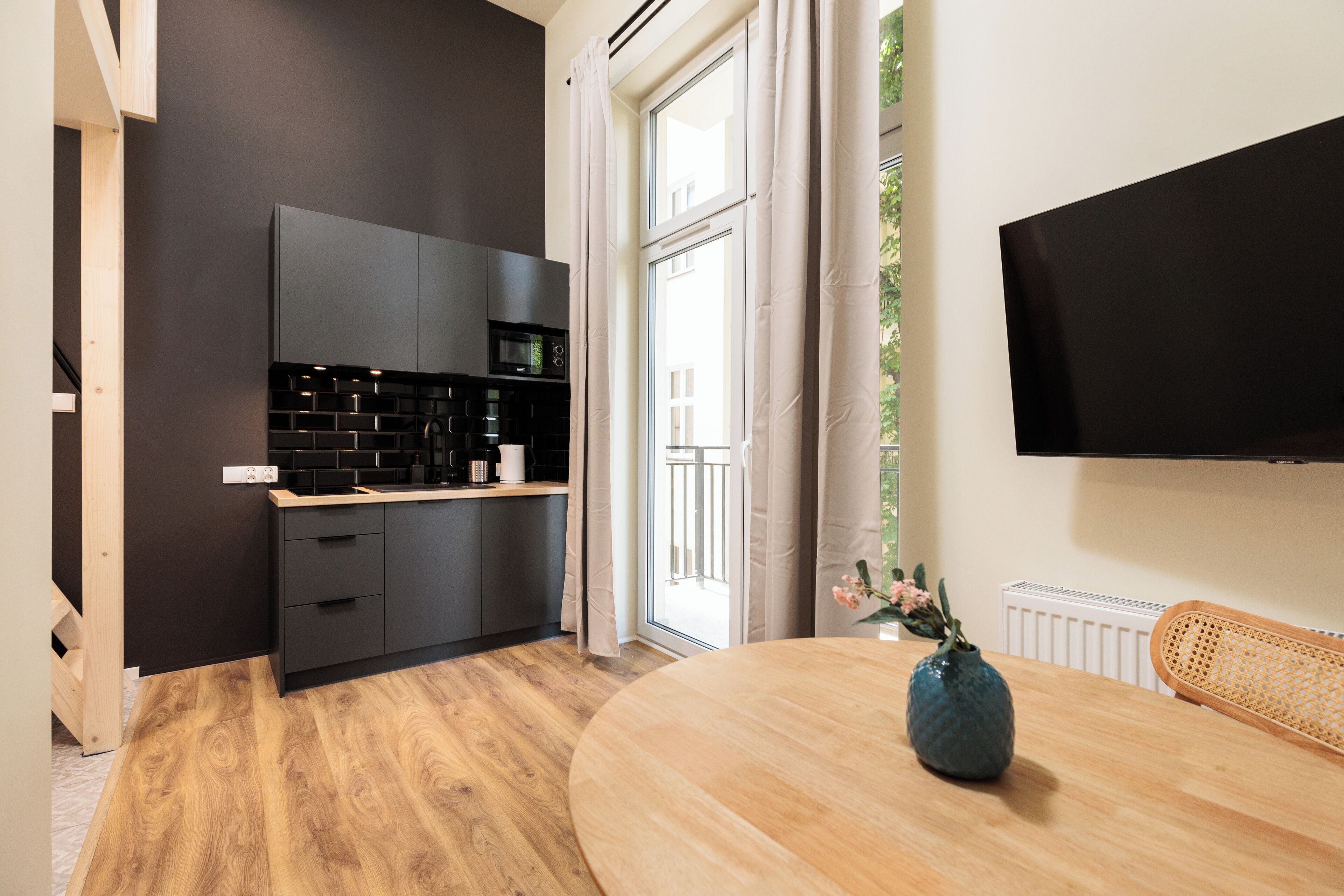 A modern kitchen with dark cabinetry, a wooden countertop, and a built-in microwave.