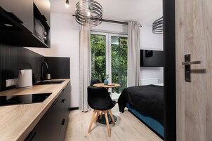 Quarto compacto e moderno com cozinha compacta, espaço de refeições e cama.