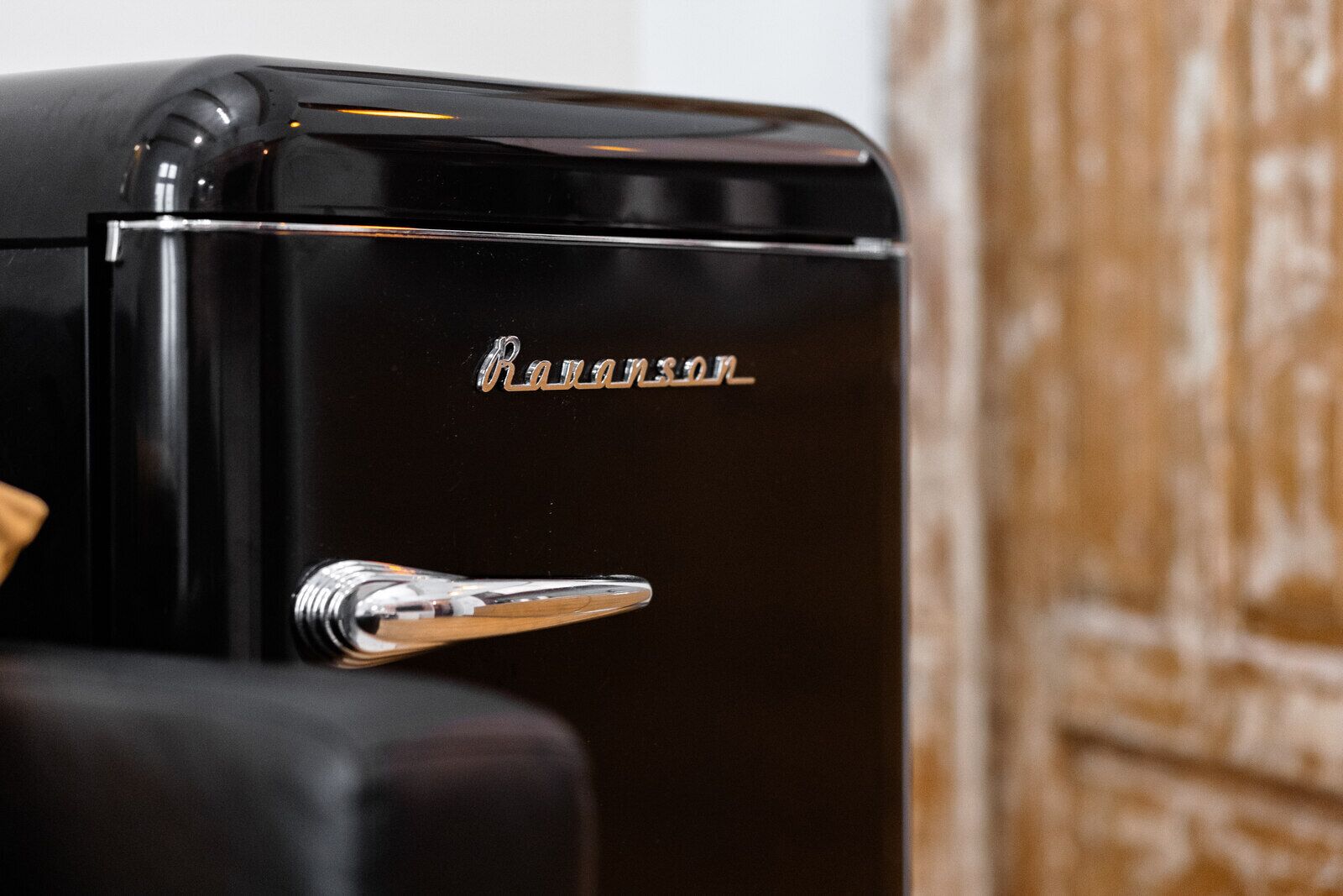 A black refrigerator with a chrome handle and the brand name "Ravenu" visible on the front.