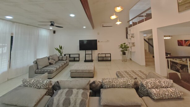 A modern living room with a sofa set, a flat-screen TV, and pendant lights. - Taman Duta KL Deluxe Villa by uBook (Kuala Lumpur)
