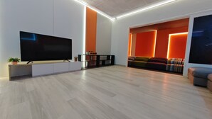 A modern living room with a flat-screen TV, a sofa, and a coffee table. - Taman Duta KL Deluxe Villa by uBook (Kuala Lumpur)