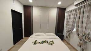 A bedroom with a bed, a black door, a wall-mounted air conditioner, and a window with curtains. - Taman Duta KL Deluxe Villa by uBook (Kuala Lumpur)