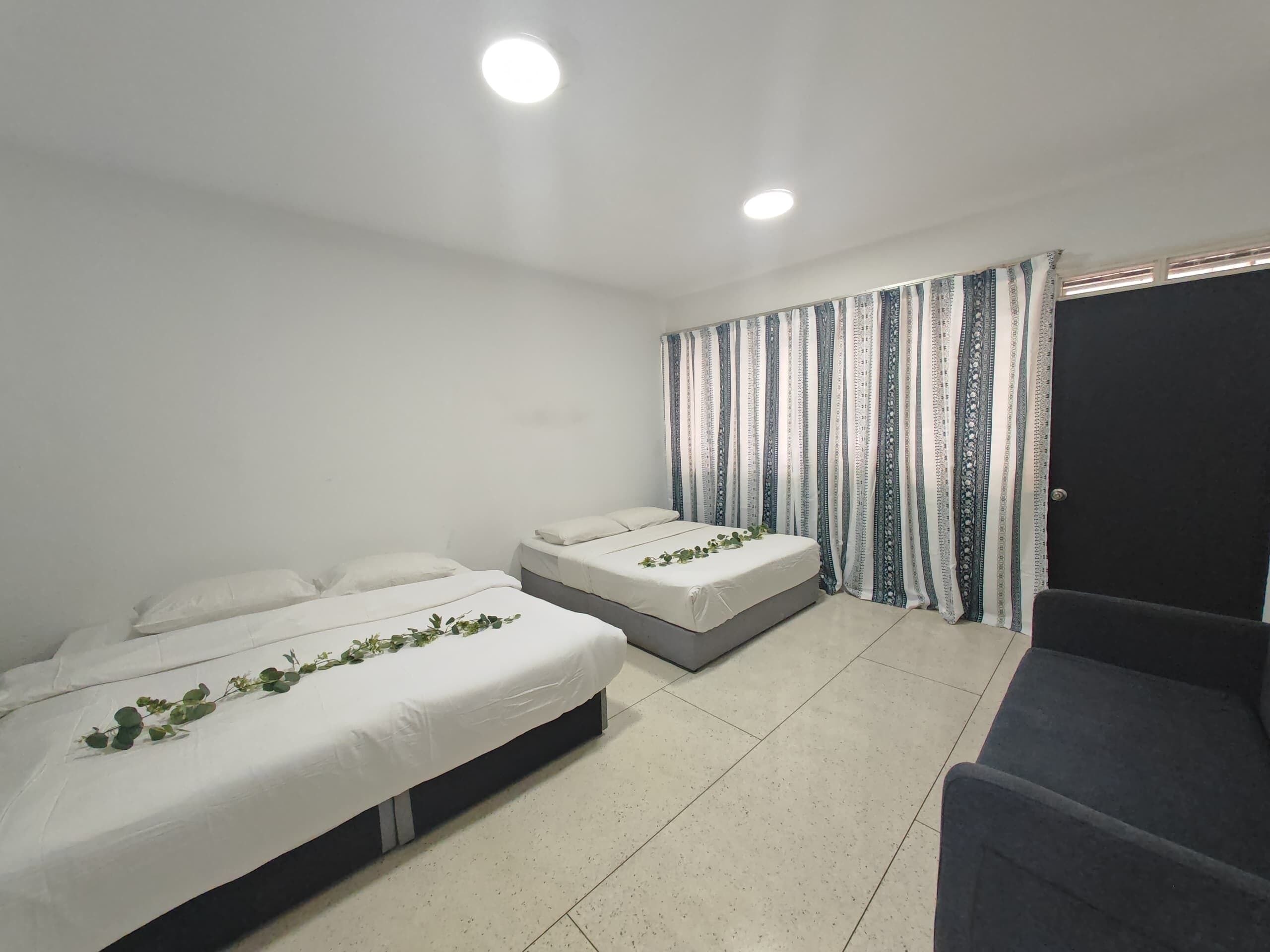 A hotel room with two single beds, a sofa, and a curtain with a striped pattern.