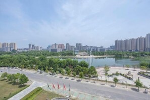 Un parco con un lago, circondato da alberi e una strada con auto parcheggiate.