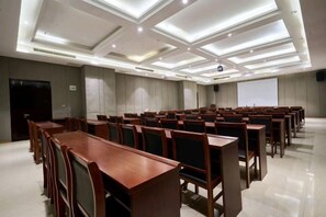 A conference room with rows of wooden tables and chairs, a projector screen, and a whiteboard. - Yilong International Hotel (Xincai Moon Bay Park) (Xincai)
