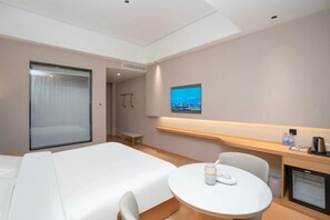 A hotel room with a bed, a round table with a candle, a TV on the wall, and a small desk with a coffee maker. - Yilong International Hotel (Xincai Moon Bay Park) (Xincai)