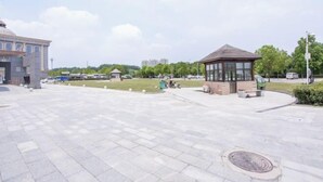 Une vaste place centrale agrémentée d’un kiosque, d’un bâtiment surmonté d’un dôme et de quelques voitures garées.