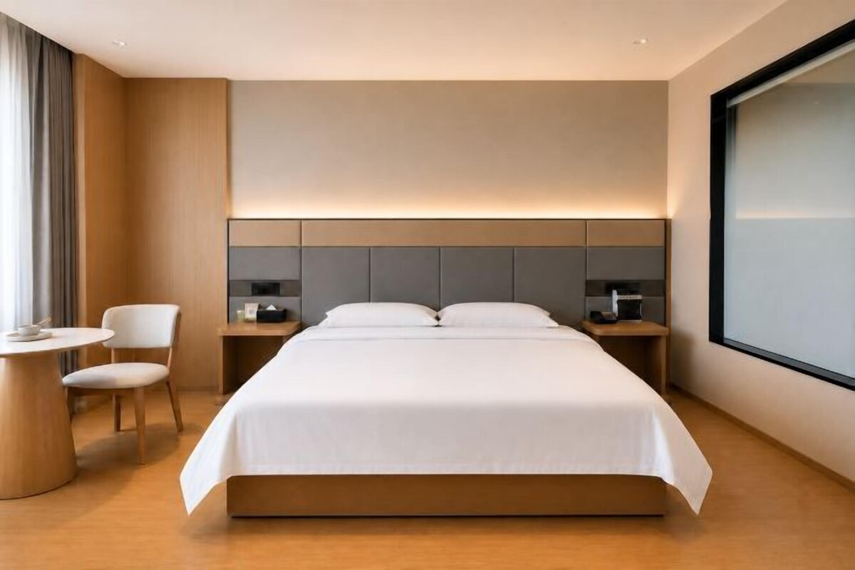 Una habitación de hotel moderna con una cama grande, mesitas de noche, un escritorio y una silla.