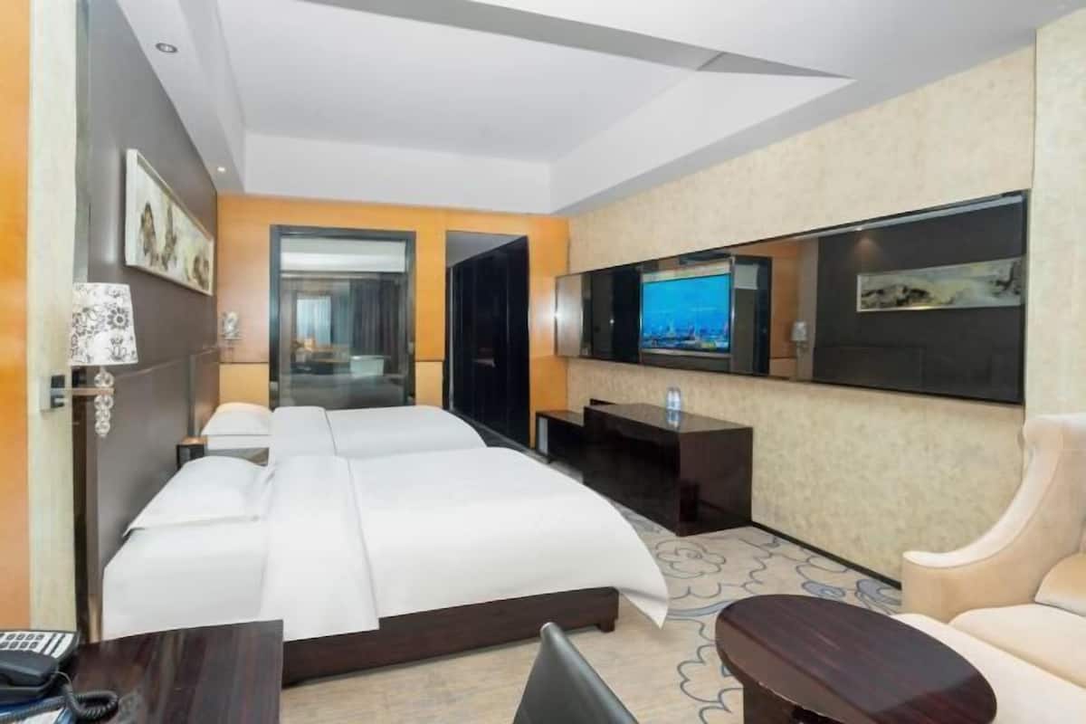 A hotel room with a large bed, a TV mounted on the wall, a desk, and a chair.