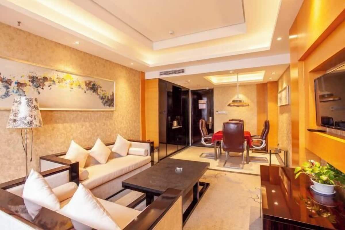 A modern hotel room with a sofa, a dining table, and a TV.