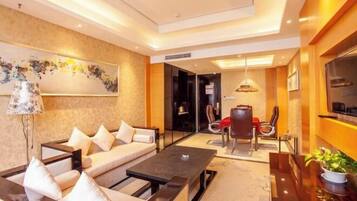 A modern hotel room with a sofa, a dining table, and a TV.