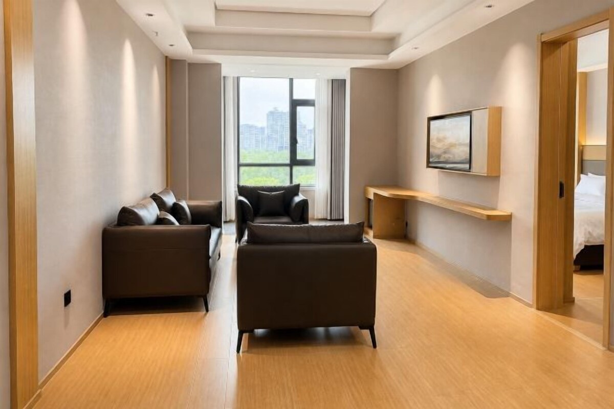 Pasillo de hotel con un conjunto de sofás, piso de madera, un cuadro en la pared y vistas a través de la ventana.