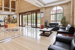 A spacious lobby with a reception desk, seating area, and large windows. - Yilong International Hotel (Xincai Moon Bay Park) (Xincai)