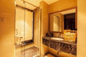 Un baño moderno con cabina de ducha de vidrio, lavamanos de mármol y un espejo grande.