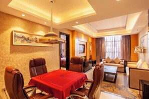 A hotel room with a dining area, a sofa, and a TV. - Yilong International Hotel (Xincai Moon Bay Park) (Xincai)