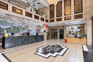Un vestíbulo de hotel con una recepción, un mural grande y un diseño decorativo en el suelo.