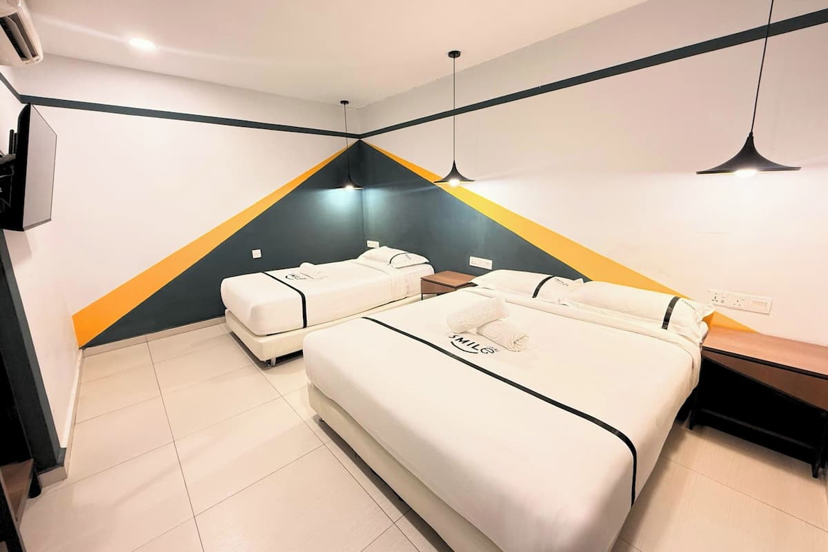 Une chambre d’hôtel moderne avec deux lits, un bureau et un petit coin salon.