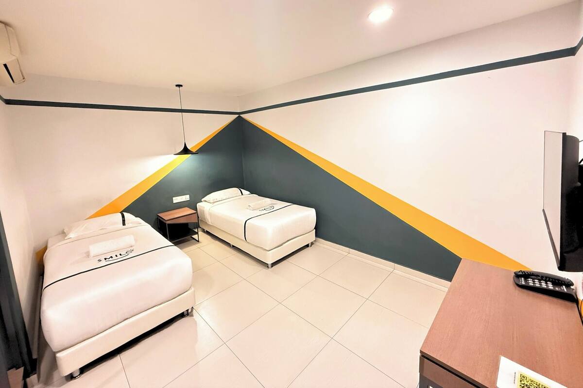 Une chambre d’hôtel avec un lit, un bureau, une chaise et un téléviseur.