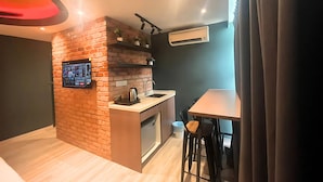 Une cuisine compacte avec un mur d’accent en briques, une cuisinière intégrée, un évier et un petit coin repas équipé de deux tabourets.