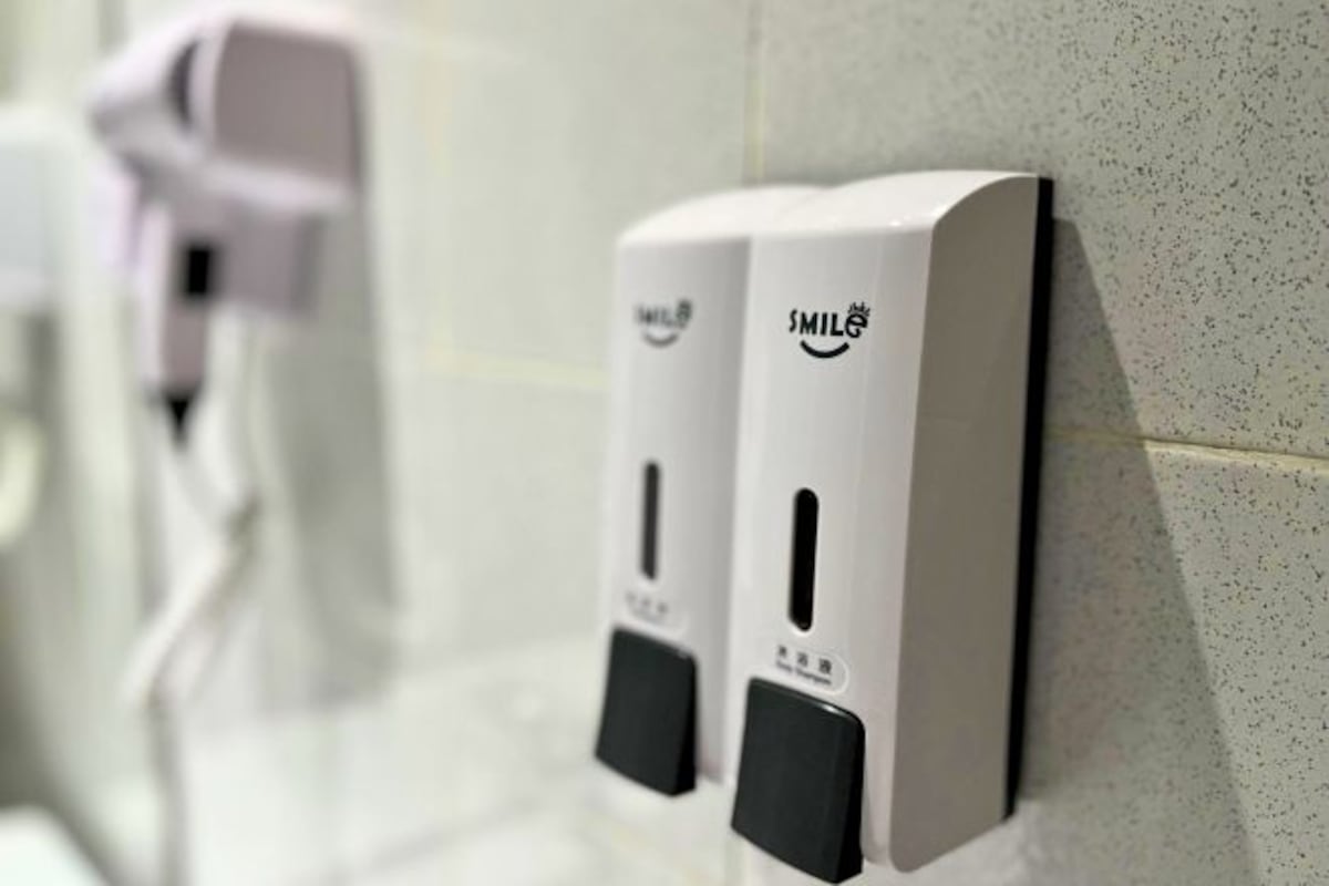 A row of hand sanitizer dispensers mounted on a tiled wall.