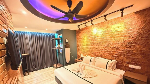 Une chambre d’hôtel moderne avec un grand lit, un ventilateur de plafond, un mur en briques et un mur en pierre.
