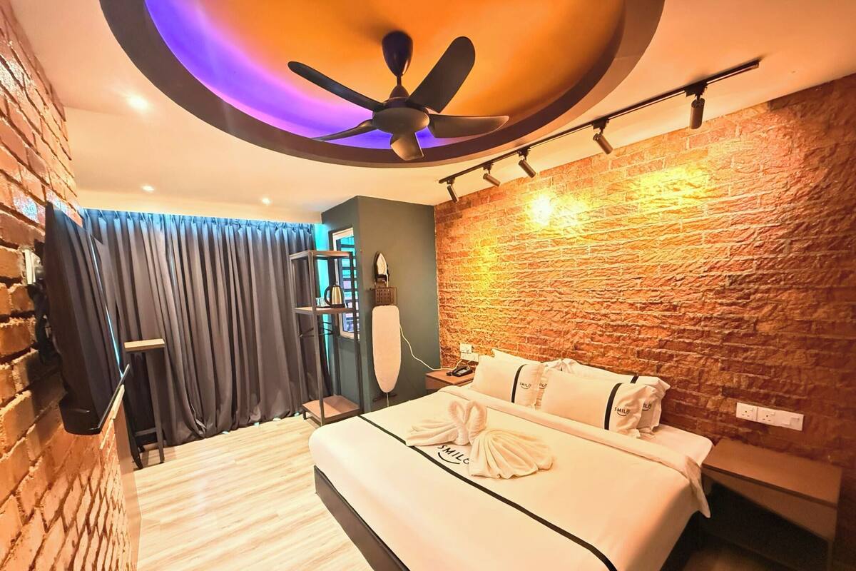 Une chambre d’hôtel moderne avec un grand lit, un ventilateur de plafond, un mur en briques et un mur en pierre.