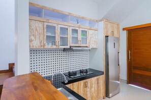 A kitchen with wooden cabinets, a black countertop, a stainless steel refrigerator, and a wooden door. - Villa Royal Pandawa Ungasan (Bali)