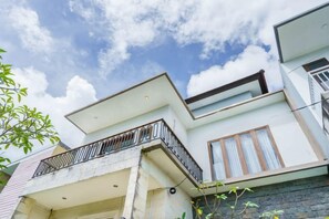 Una casa moderna de dos pisos con balcón, garaje y cielo despejado.