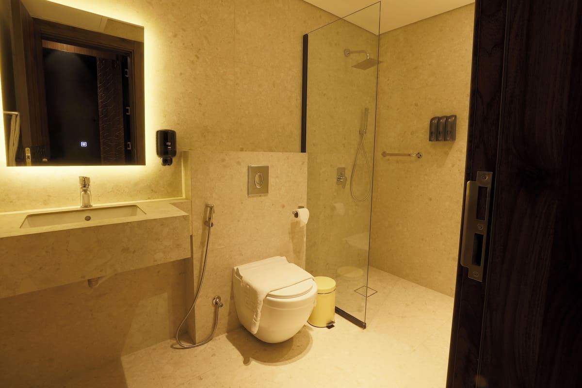 A modern bathroom with a glass-enclosed shower, a white toilet, and a sink with a mirror above it.