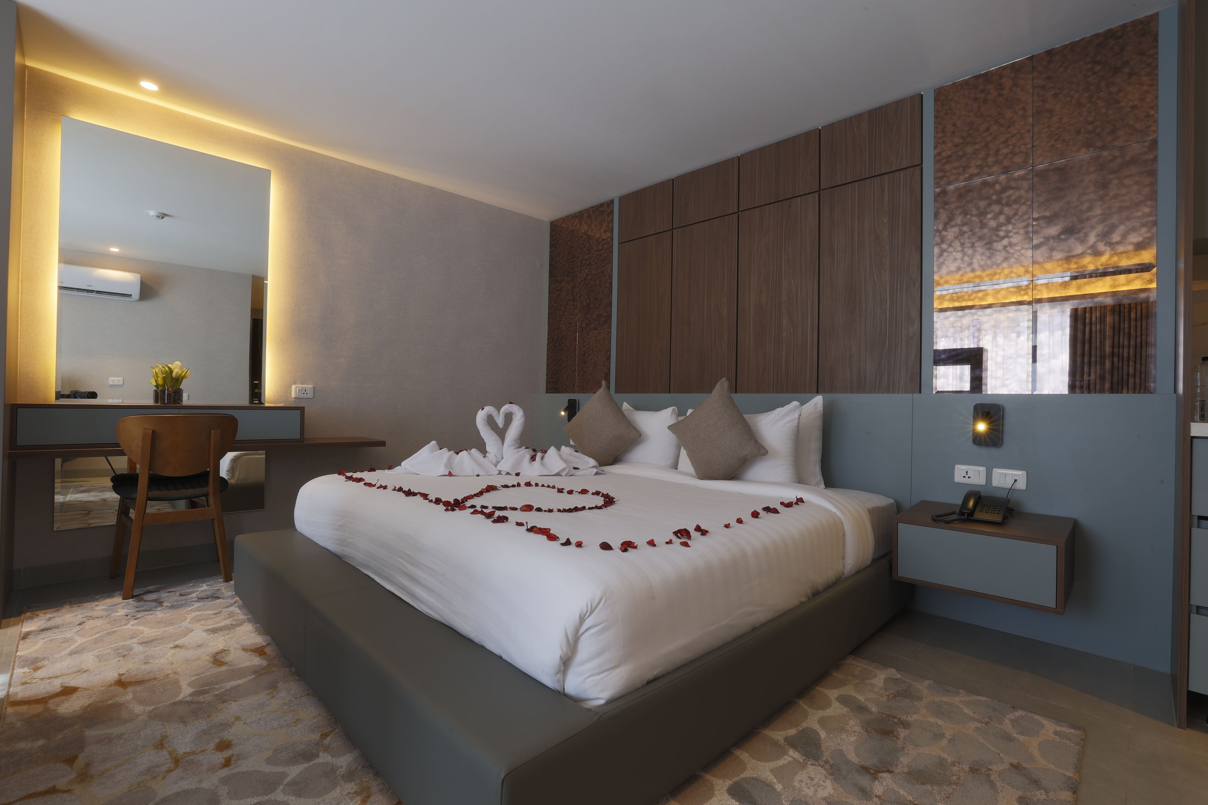 A modern bedroom with a large bed, a desk, and a chair.