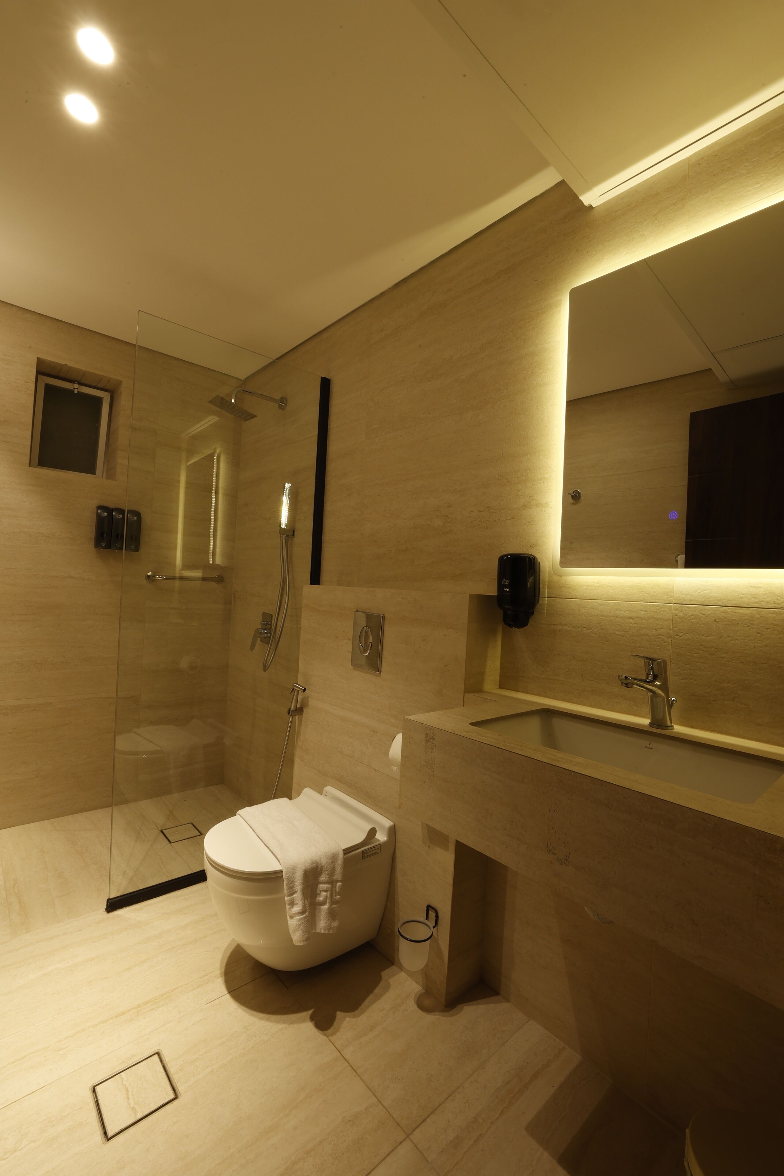 Un baño moderno con ducha de vidrio, inodoro y lavamanos con espejo.