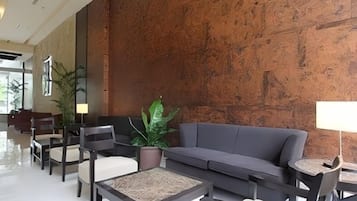 A lobby with a grey sofa, chairs, a coffee table, and a potted plant.