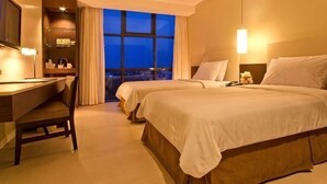 A hotel room with a desk, two beds, a view of the city, and a large window. - B Hotel Alabang (Muntinlupa)