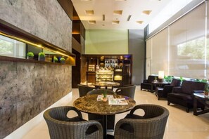 Een bar met een ronde tafel en rieten stoelen, een bar met flessen en een groot raam met uitzicht.