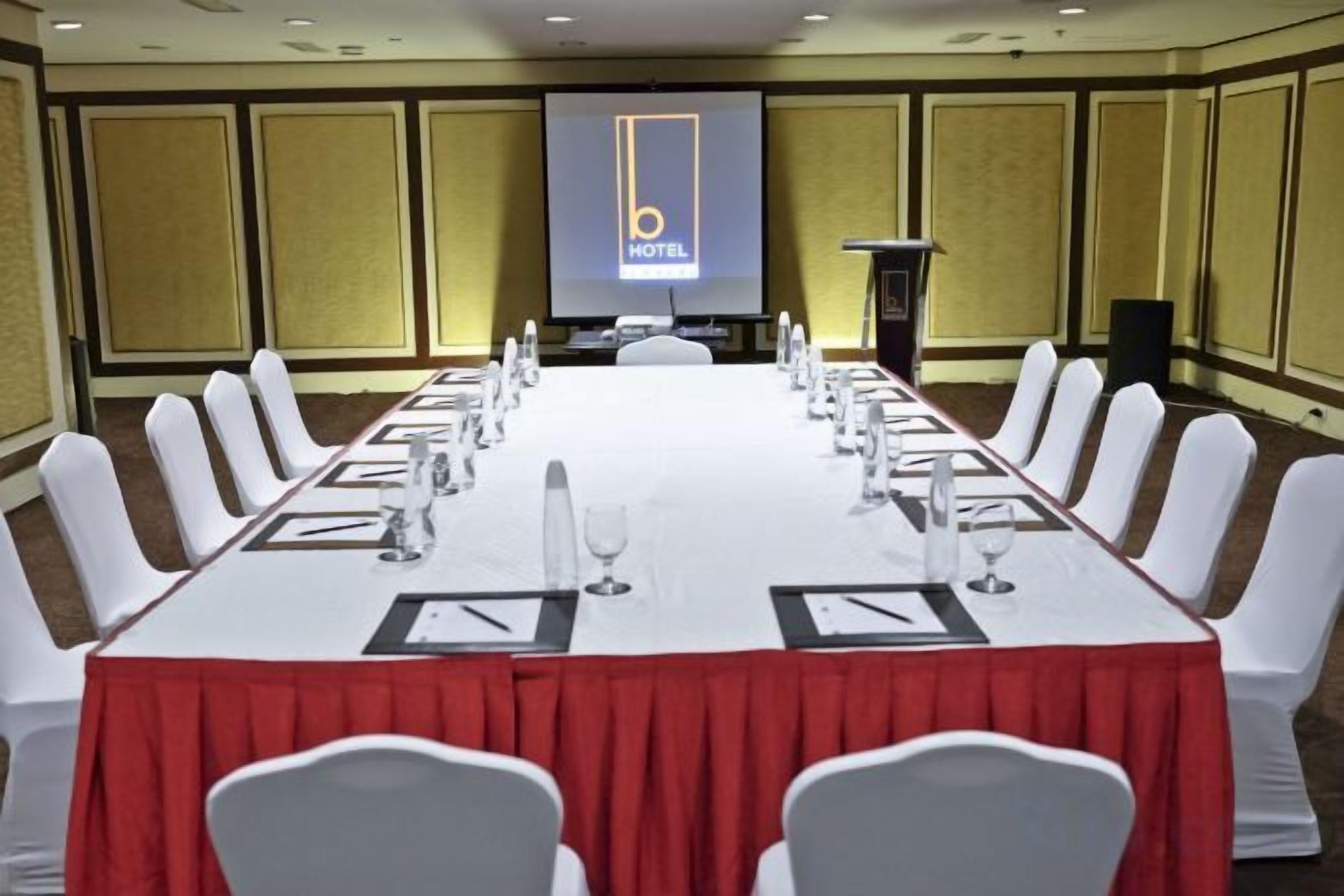 A conference room with a long table, white chairs, and a podium.