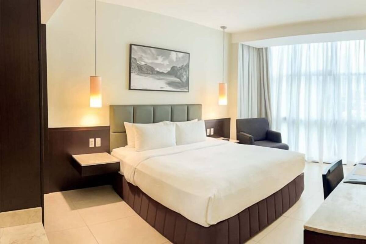 Ein Hotelzimmer mit einem großen Bett, Nachttischen, einem Schreibtisch und einem Sessel.