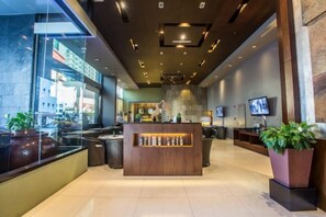 A modern hotel lobby with a reception desk, seating area, and large windows. - B Hotel Alabang (Muntinlupa)