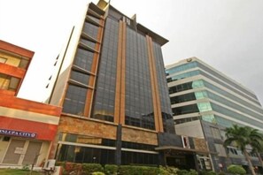 Un edificio de varios pisos con un diseño arquitectónico moderno, que destaca por su fachada de vidrio y techo plano.
