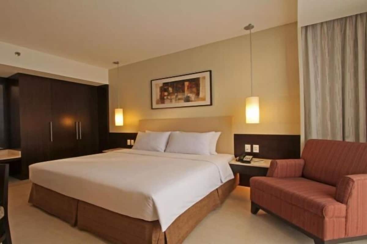 Ein Hotelzimmer mit einem großen Bett, einem Schreibtisch, einem Stuhl und einem Gemälde an der Wand.