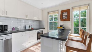 Una cocina moderna con armarios blancos, encimera negra y isla de madera con asientos.