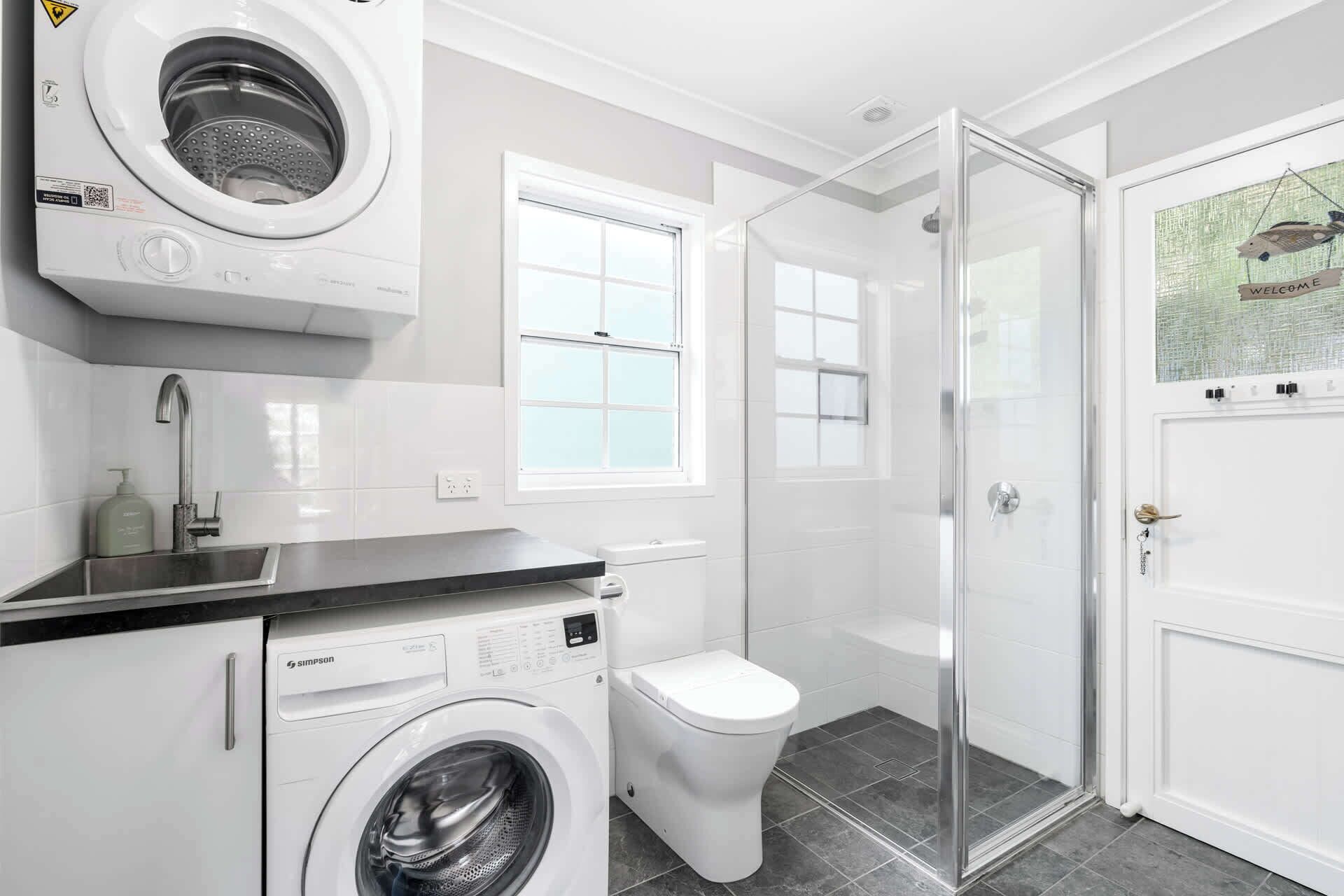 A modern bathroom with a washing machine, toilet, and shower.