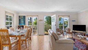 Un salón amplio con una mesa de comedor, sillas, un sofá y una televisión.