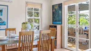 Un comedor con mesa de vidrio, sillas de madera, un jarrón de flores y un mapa en la pared.