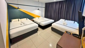 Ein Hotelzimmer mit drei Einzelbetten, einem Schreibtisch mit Computer und einem großen Fenster mit Vorhängen.