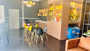 Eine moderne Küche mit Barbereich, einer Sitzgruppe mit bunten Stühlen und einem Automaten.