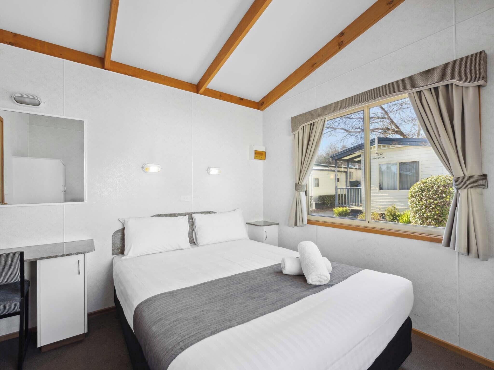 A bedroom with a bed, bedside table, and a window with curtains.